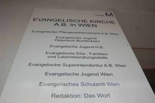 Info-Schild an der Hauswand über die verschiedenen Arbeitsbereiche und Einrichtungen.