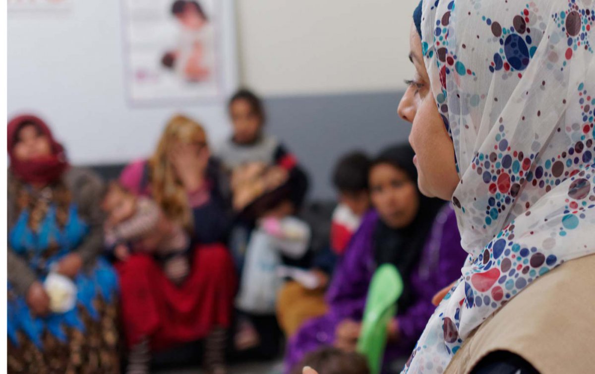 Im Vordergrund sieht man das Profil einer muslimischen Frau mit Kopftuch, im Hintergrund, der unscharf fotografiert ist, sind weitere Frauen zu erkennen.