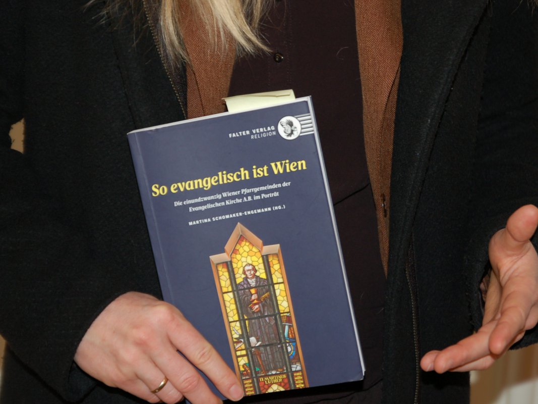 in Händen gehalten wird das Buch &quot;So evangelisch ist Wien&quot;